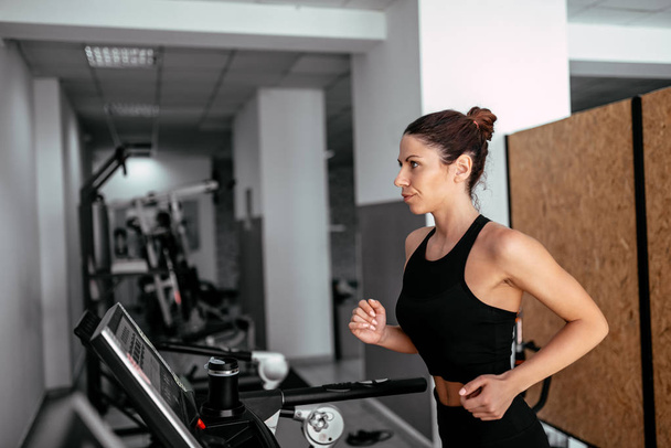 attractive sport woman running on treadmill in gym  - Фото, изображение