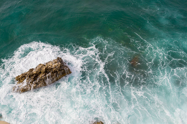 Big waves breaking on the shore. Waves and white foam. Coastal stones. View from above. The marine background is green - Photo, Image