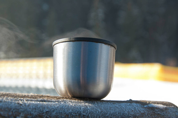 Le capuchon de la fiole à vide avec du thé chaud fumant à l'extérieur à la journée d'hiver ensoleillée et givrée
 - Photo, image