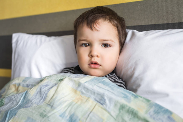 sairas surullinen vauva poika makaa sängyllä
 - Valokuva, kuva