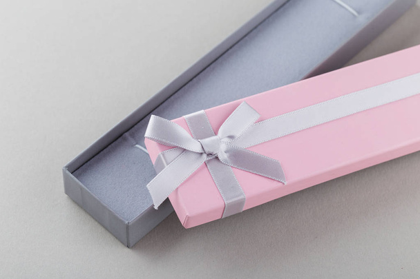 Open pink gift box with ribbon bow on gray background. Long paper present box for jewelry or bracelet  - Photo, Image