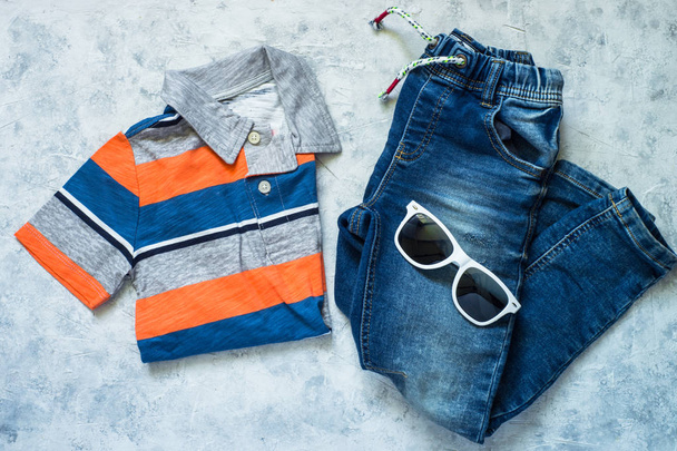 Child clothes - jeans, polo and sunglasses top view. - Photo, Image
