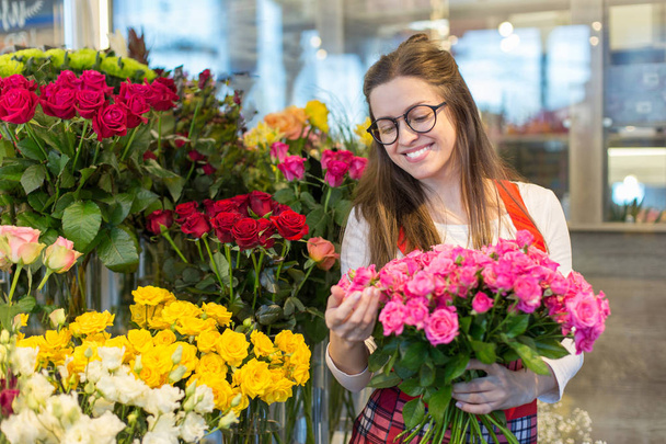 flower seller, young woman standing at shop with  flower in hands happily looks at camera - Valokuva, kuva