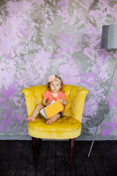 Little girl is sitting in a chair. - Fotó, kép