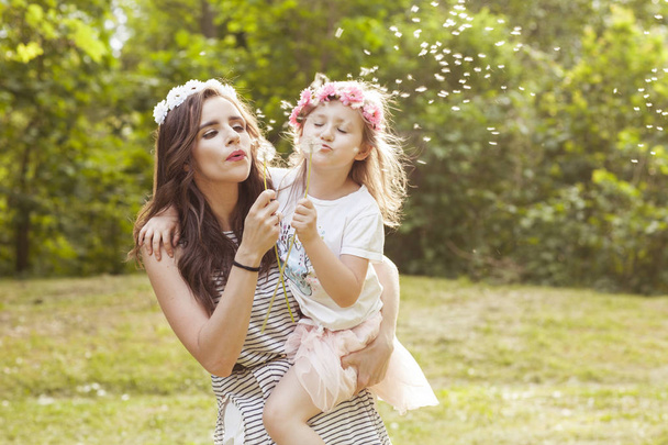 Mum and daughter blowing the dandelion flower. - Photo, Image