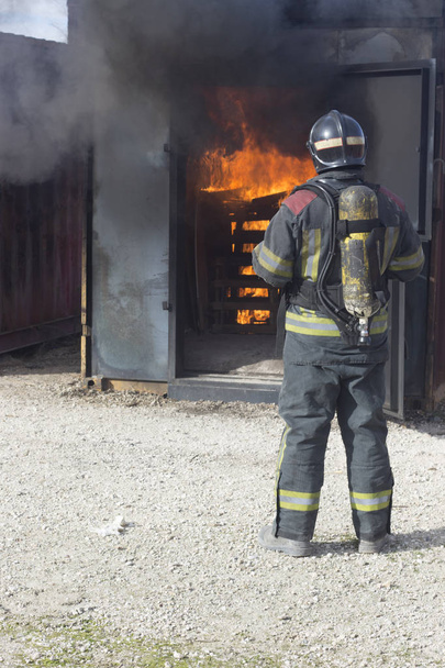 Strażak gaszący pożarową stację szkoleniową gaśnica Backdraft awaryjne ćwiczenia bezpieczeństwa. - Zdjęcie, obraz
