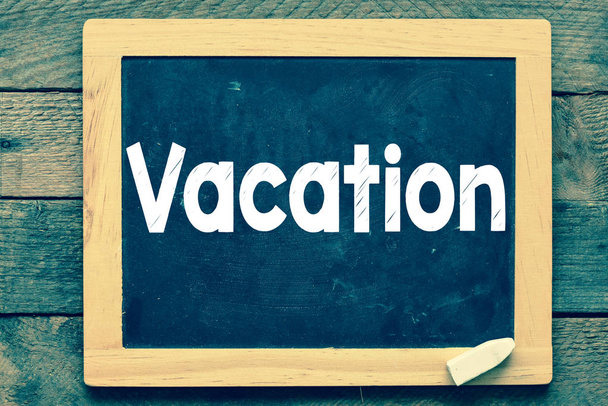Vacation inscription on a blackboard on the wooden background  - Photo, Image