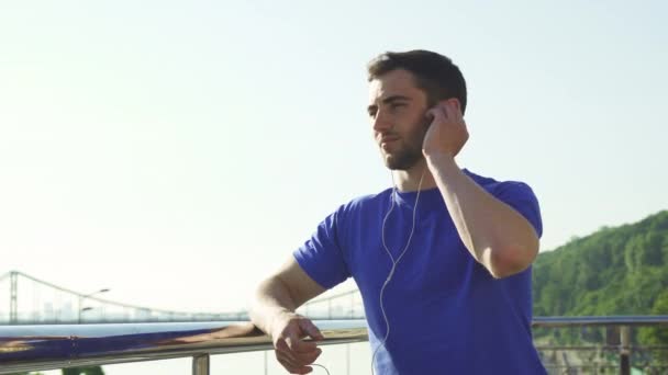 Feliz hombre guapo disfrutando escuchando música al aire libre después de hacer ejercicio
 - Metraje, vídeo