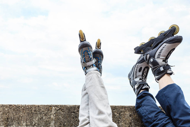 Closeup of people friends with roller skates. Woman and man relaxing outdoor. - 写真・画像