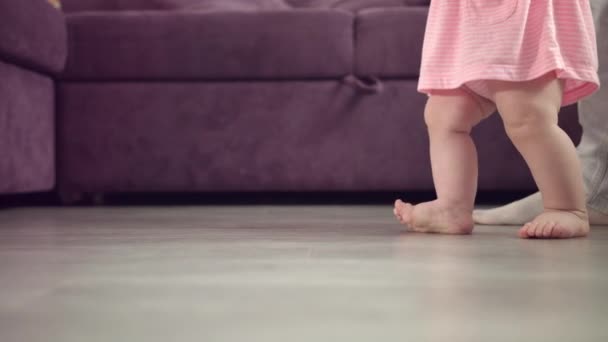 Kid jalat kävely lattialla. Vauvan jalat astuvat kotiin. Lapsen ensimmäinen askel - Materiaali, video