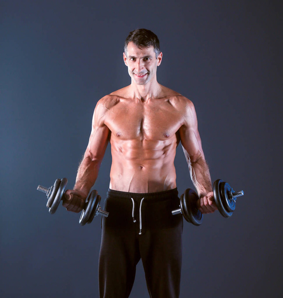 Handsome muscular man working out with dumbbells. Personal fitness instructor. Personal training. - Foto, Imagem