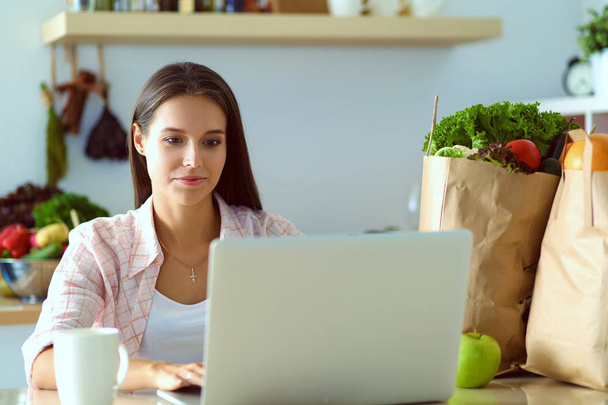 Улыбающаяся женщина онлайн покупки с помощью планшета и кредитной карты на кухне. Улыбающаяся женщина - Фото, изображение