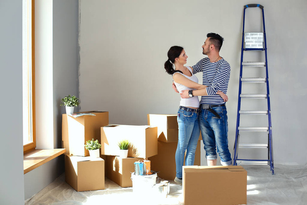 Happy young couple unpacking or packing boxes and moving into a new home. young couple - Фото, изображение