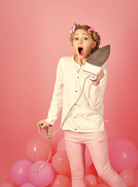 Child ironing clothes on pink background, punchy pastels. - Foto, afbeelding
