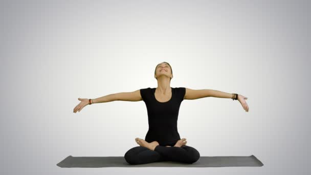 Young woman meditates while practicing yoga on white background - Materiał filmowy, wideo