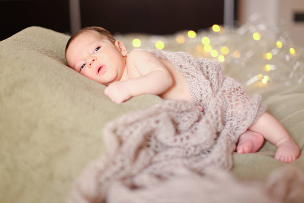 Μικρό όμορφο μωρό ξαπλωμένη σε κουβέρτα με βλέμματα στο παρασκήνιο. - Φωτογραφία, εικόνα