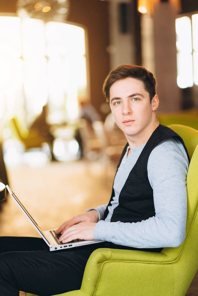 Young man with pc computer sits in a comfortable chair - Photo, Image