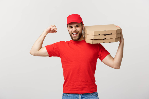 Delivery Concept - Porträt eines starken, gut aussehenden Zustellers, der seine Muskeln spielen lässt und Pizzakartons in der Hand hält. Isoliert auf grauem Studiohintergrund. Kopierraum. - Foto, Bild