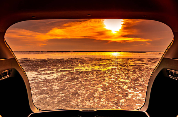 Όμορφη θέα στη θάλασσα από μέσα στο πορτ-μπαγκάζ αυτοκινήτου. Θέα στη θάλασσα με πορτοκαλί του ουρανού και τα σύννεφα στο ηλιοβασίλεμα στην παραλία. Ελευθερία καλοκαιρινά ταξίδια με οδικό ταξίδι διακοπές έννοια. Ρομαντική θέα το βράδυ. - Φωτογραφία, εικόνα