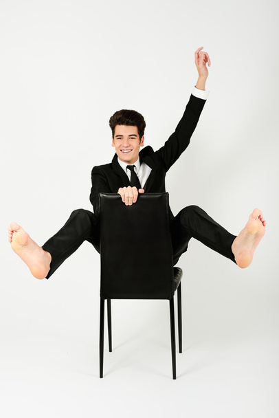 Boldog üzletember ül egy széken, felemelt karral - Fotó, kép