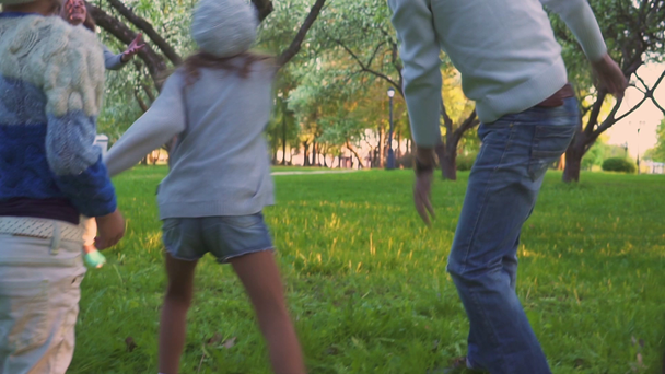 Οι γονείς και οι δύο κόρες αθλούνται με μπάλα στο πάρκο άνοιξη στον ανθισμένο κήπο. Ενεργό αναψυχή. - Πλάνα, βίντεο