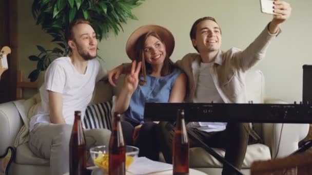Cheerful friends musicians are taking selfie with smartphone having fun, posing, gesturing and laughing. Young people, modern technology and social media concept. - Materiał filmowy, wideo