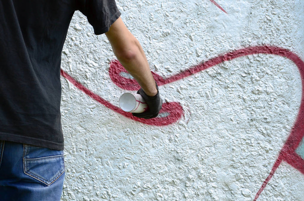 Ein junger Hooligan bemalt eine Betonwand mit Graffiti. Illegaler Vandalismus. Straßenkunst. - Foto, Bild