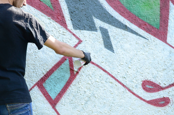 Egy fiatal huligán fest graffiti egy betonfalnak. Illegális rongálás fogalmát. Street art. - Fotó, kép