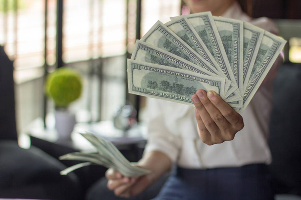 Бізнес-леді тримає доларові валютні банкноти в офісі
 - Фото, зображення
