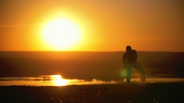O lutador faz um suporte de mão no fundo do sol poente, em câmera lenta
 - Filmagem, Vídeo