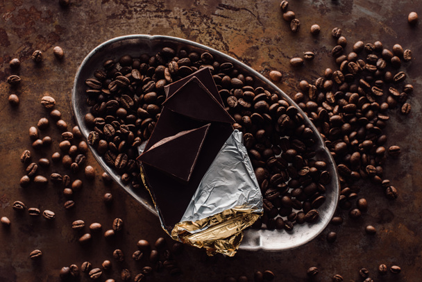 підвищений вид шоколаду у фользі та кавових зернах у срібному підносі на сільському столі
 - Фото, зображення