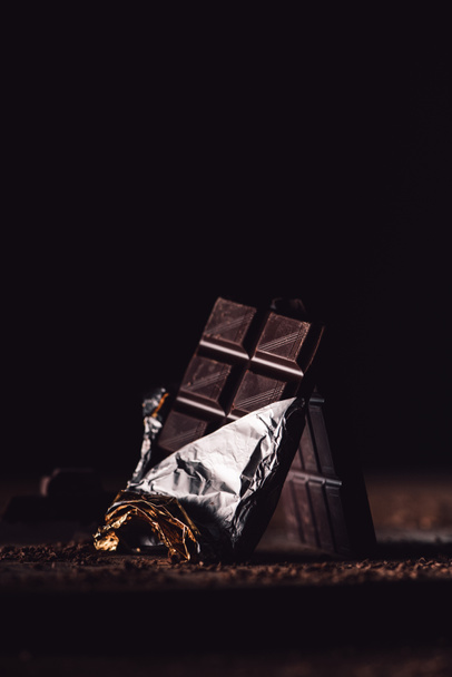 close up view of two arranged chocolate bars on wooden table on black background  - Foto, imagen