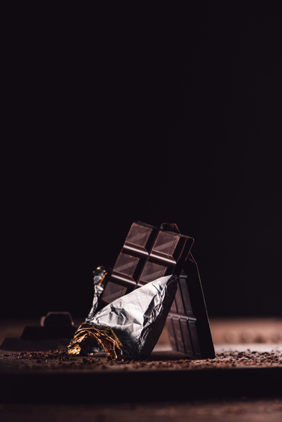 primer plano de dos barras de chocolate arregladas en la mesa de madera sobre fondo negro
  - Foto, imagen