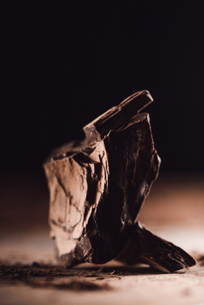 closeup image of aranged pieces of dark chocolate on wooden table on black background  - Fotó, kép