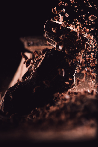  close up image of grated chocolate falling on pieces of chocolate on black background  - Foto, Imagem