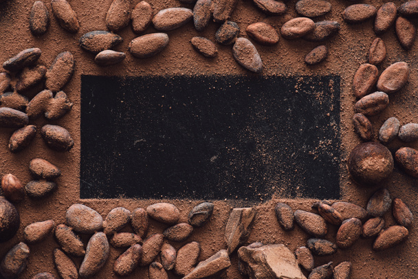 verhoogde weergave van lege oppervlak omringd cacaobonen vallende geraspte chocolade  - Foto, afbeelding