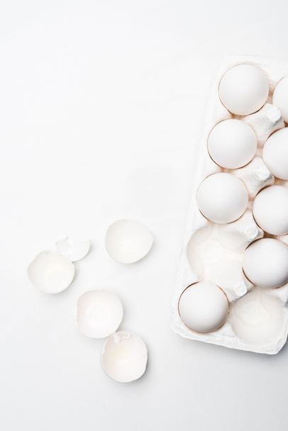 Beyaz yüzey üzerinde çiğ tavuk yumurta karton üstten görünüm - Fotoğraf, Görsel