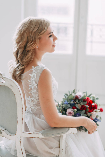 Beautiful bride in a wedding dress in a bright stylish Studio. Wedding in European style. Decor and bouquet in hand. Young girl standing, sitting and posing - Φωτογραφία, εικόνα