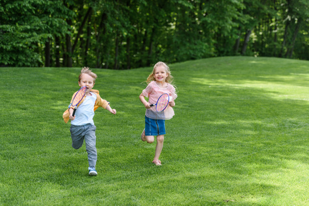 imádnivaló mosolygó gyermek ütők fut össze a parkban  - Fotó, kép