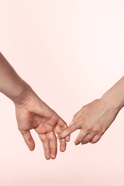 cropped shot of woman holding man hand by finger isolated on pink background  - Foto, immagini