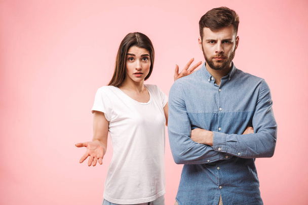 Portrait of an upset young couple having an argument isolated over pink background - Foto, immagini
