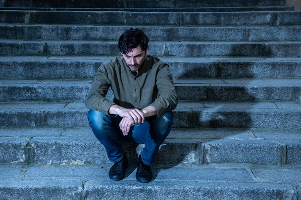 latin man stressed from work sitting on steps outside feeling anxiety in adult cause of depression and problem in living that makes you feel lonely, sad and worried in mental health concept - Foto, afbeelding