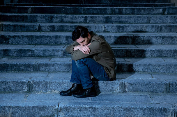 latin man stressed from work sitting on steps outside feeling anxiety in adult cause of depression and problem in living that makes you feel lonely, sad and worried in mental health concept - Photo, image