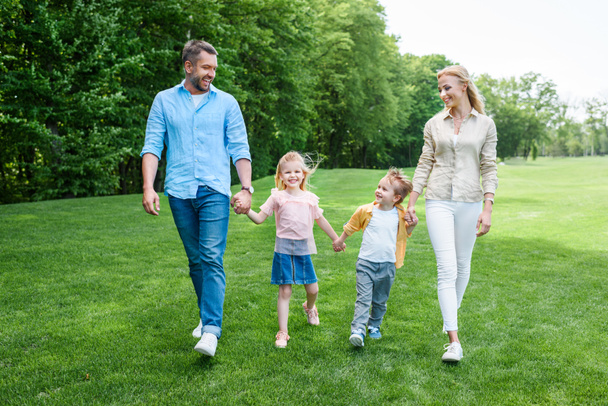 famiglia felice che si tiene per mano e cammina insieme nel parco
 - Foto, immagini