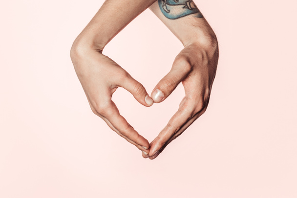 plan recadré de femme et homme tatoué faisant symbole de coeur par les mains isolées sur fond rose
  - Photo, image