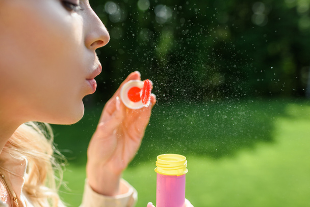 side view of young woman blowing soap bubbles in park - Фото, зображення