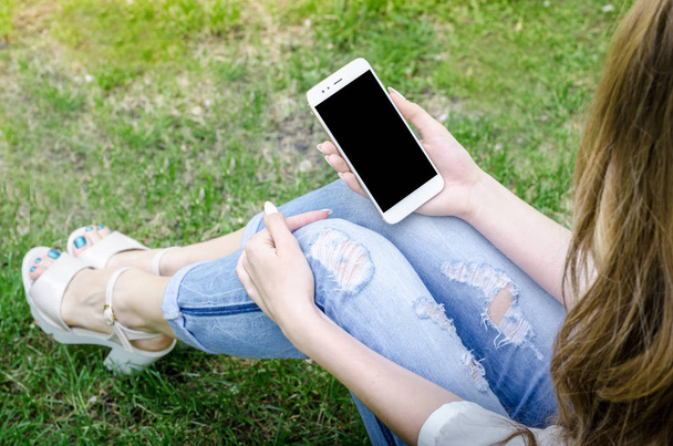 Close Up bianco Smartphone Cellulare tenuta in mano donna Elegante strappato Jeans Long Nails Denim Nero Oled Display Natura sfondo
 - Foto, immagini