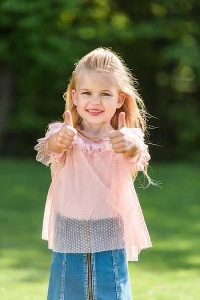 cute little child showing thumbs up and smiling at camera - Photo, Image