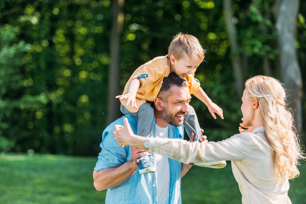 happy parents with adorable little son spending time together in park - Photo, Image