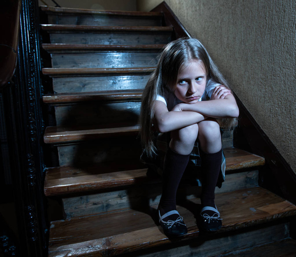 Verdrietig, depressief, ongelukkig schoolmeisje lijden pesten en misbruik eenzaam en hopeloos zittend op trap met donkere licht gevoel. School isolatie, pesterijen, intimidatie en misbruik concept - Foto, afbeelding